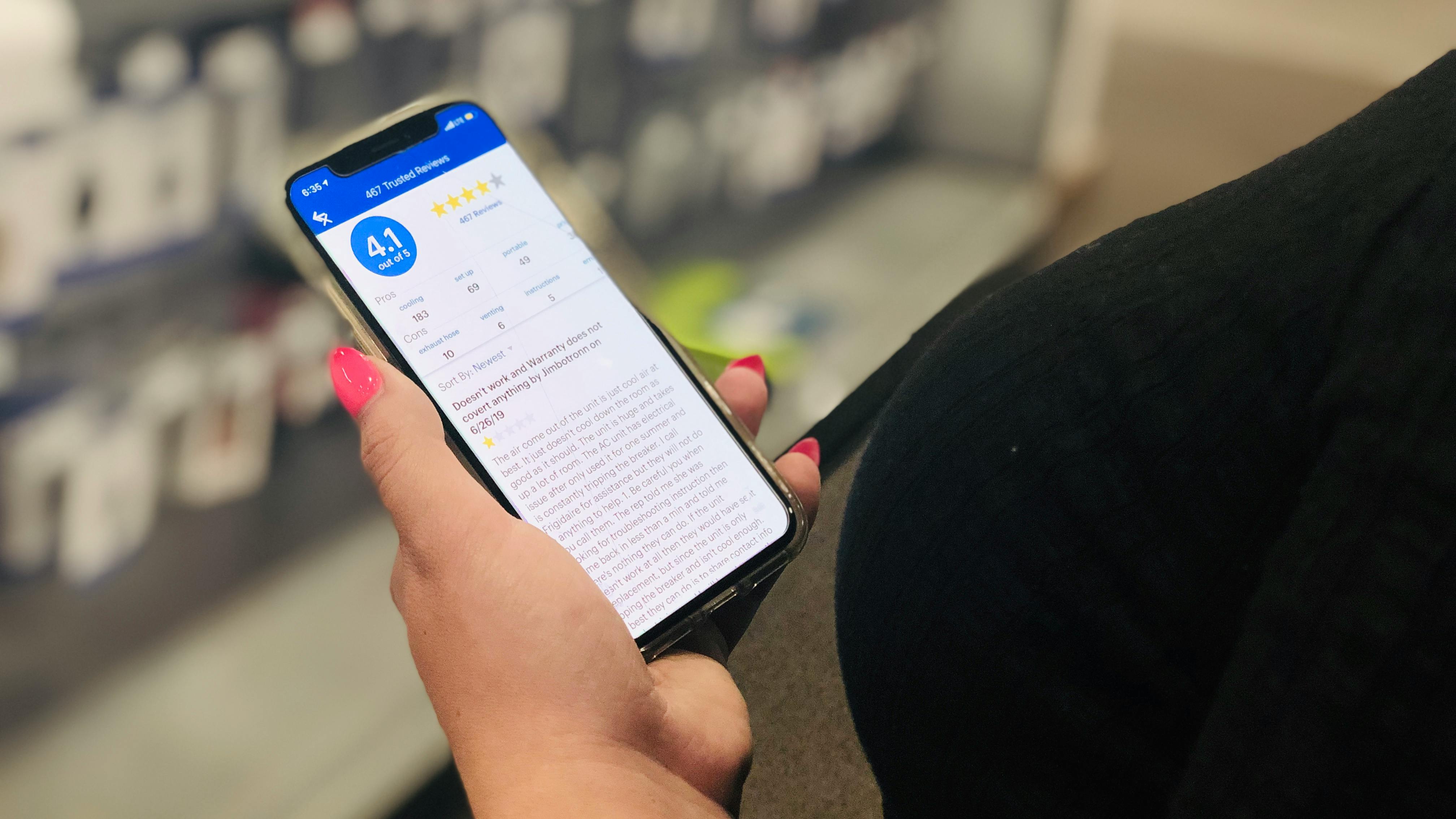 hand holds phone open to best buy app and reviews in the app