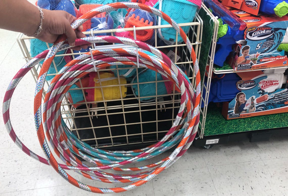 A person's hand picking up a hula hoop from a pile of them at Michael's.