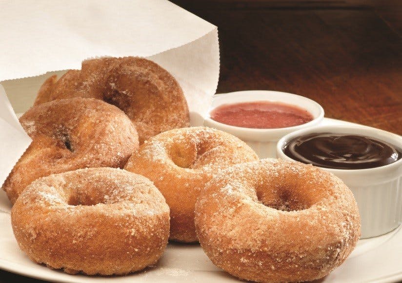 a bag of donuts with dipping sauce on table 