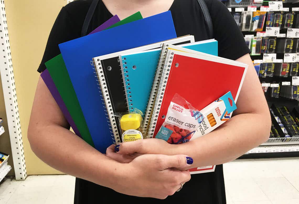 A person with their arms full of school supplies.