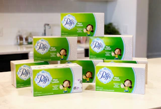 a pack of puffs plus lotion boxes on a table
