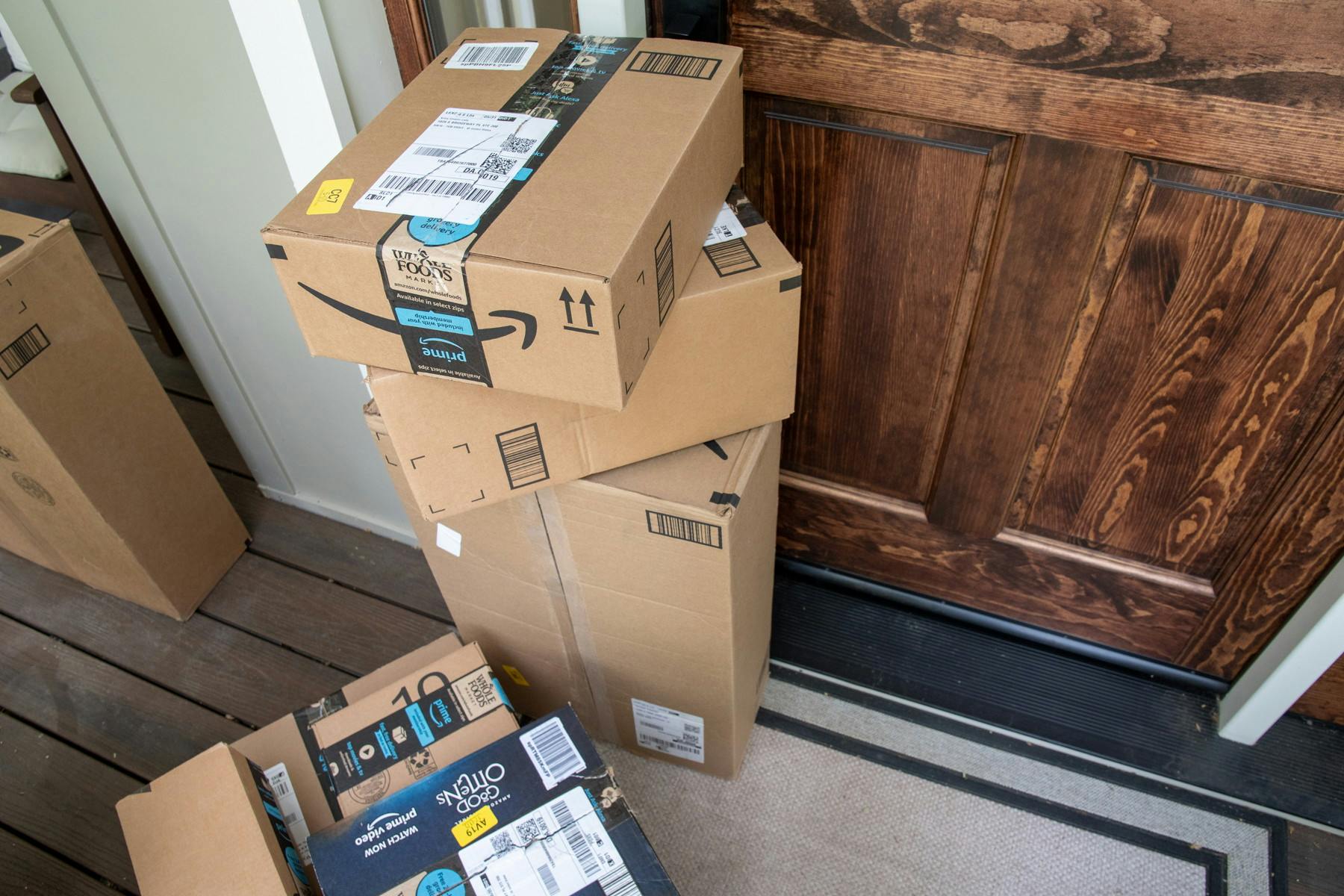 A pile of Amazon boxes stacked on a front porch.