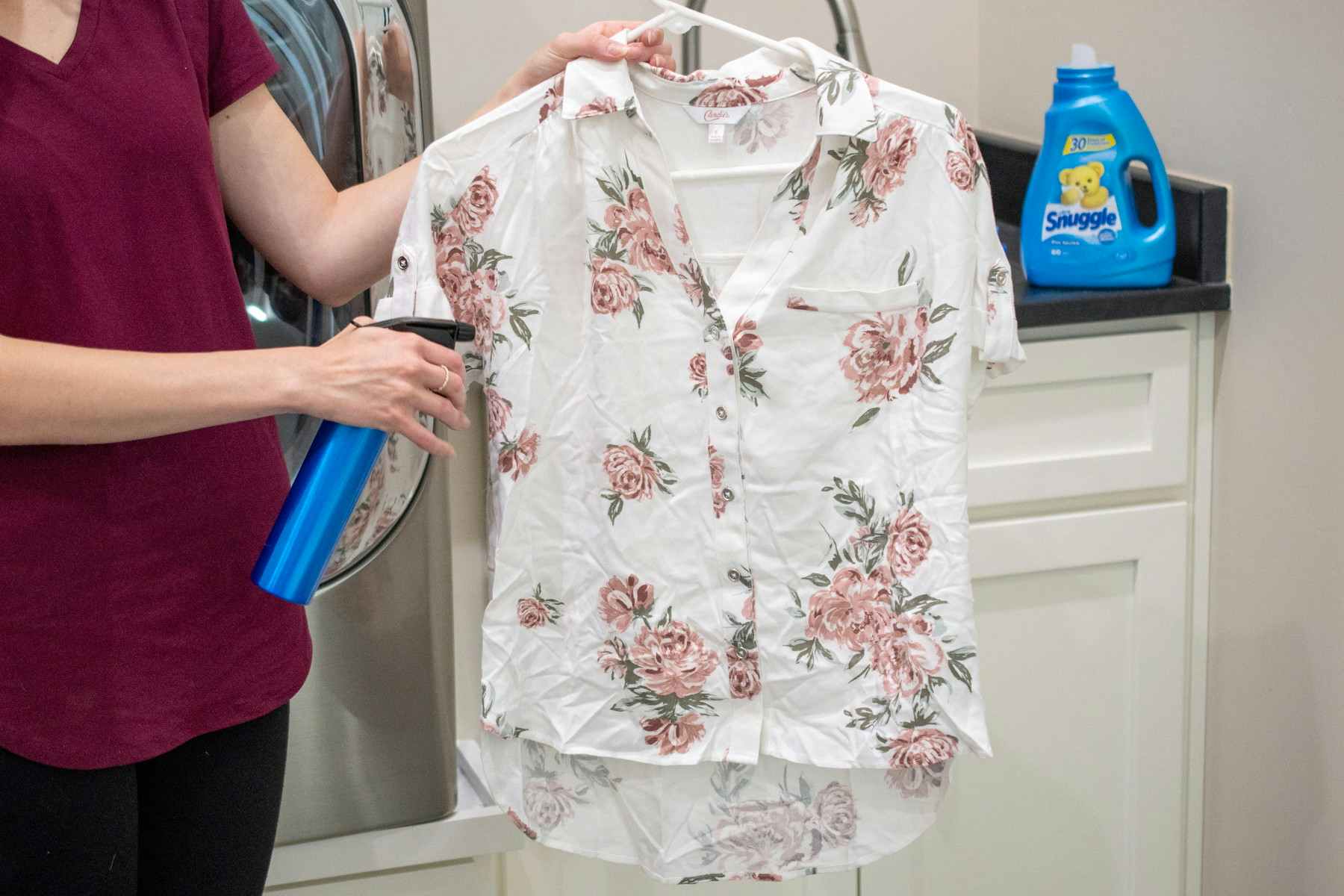 Woman spraying a wrinked shirt with homemade wrinkle release spray