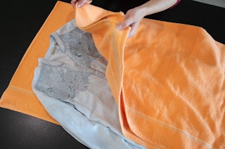 a wrinkled shirt being placed in between a damp towel