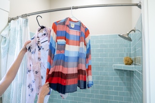 Wrinkled shirts being hung near a running shower