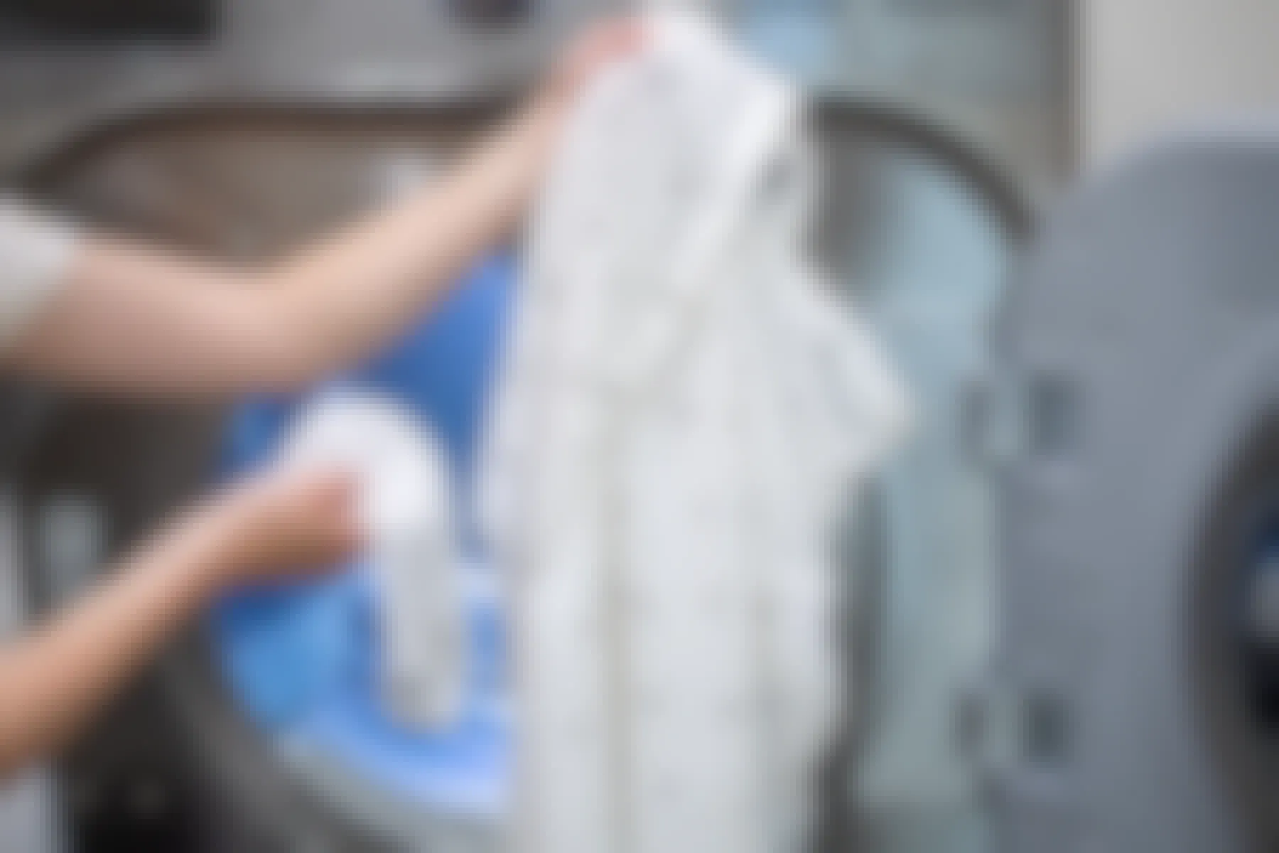 Woman holding a wet sock with a wrinkled shirt in front of a clothes dryer.