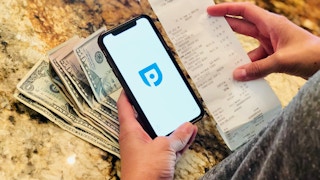 Someone using paribus on their phone while holding a receipt