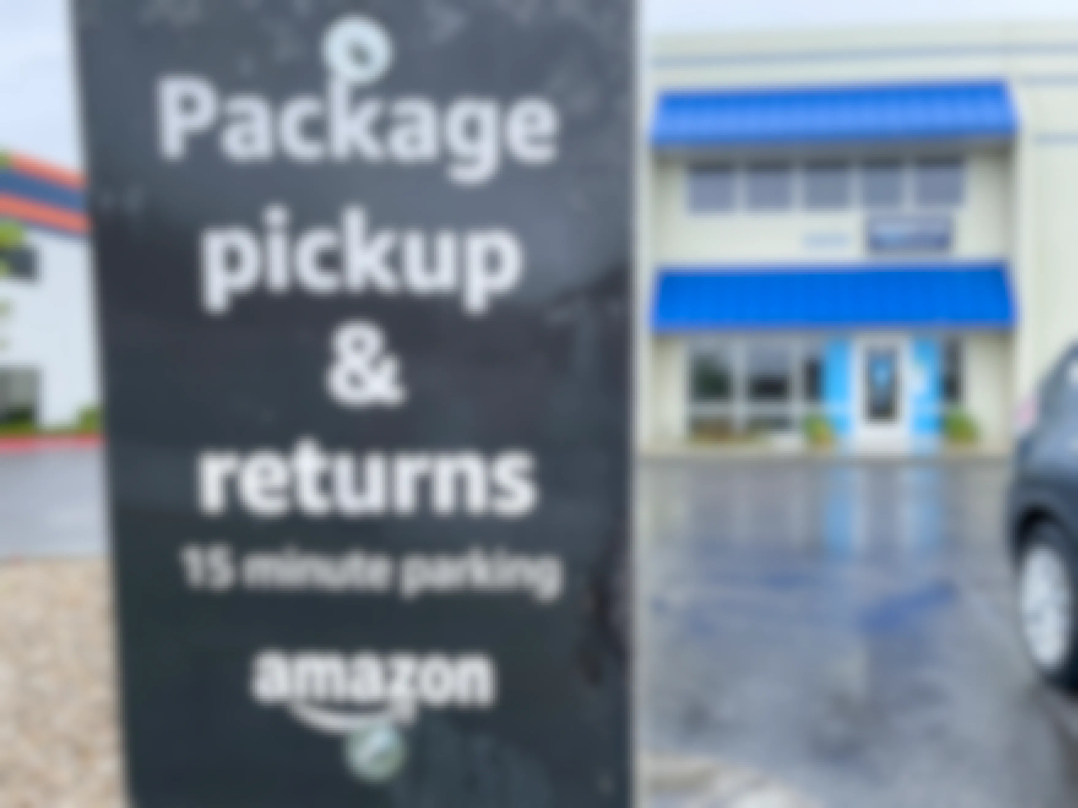 A sign outside an amazon hub location with the warehouse front entrance in the background
