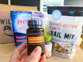 someone holding up vitamin D3 in front of groceries