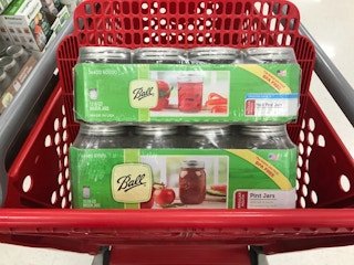 Two cases of Ball mason jars sitting in a shopping cart.