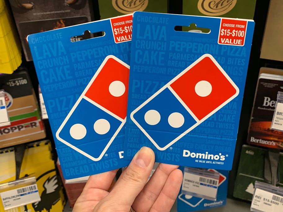 A person's hand holding up 2 Domino's gift cards