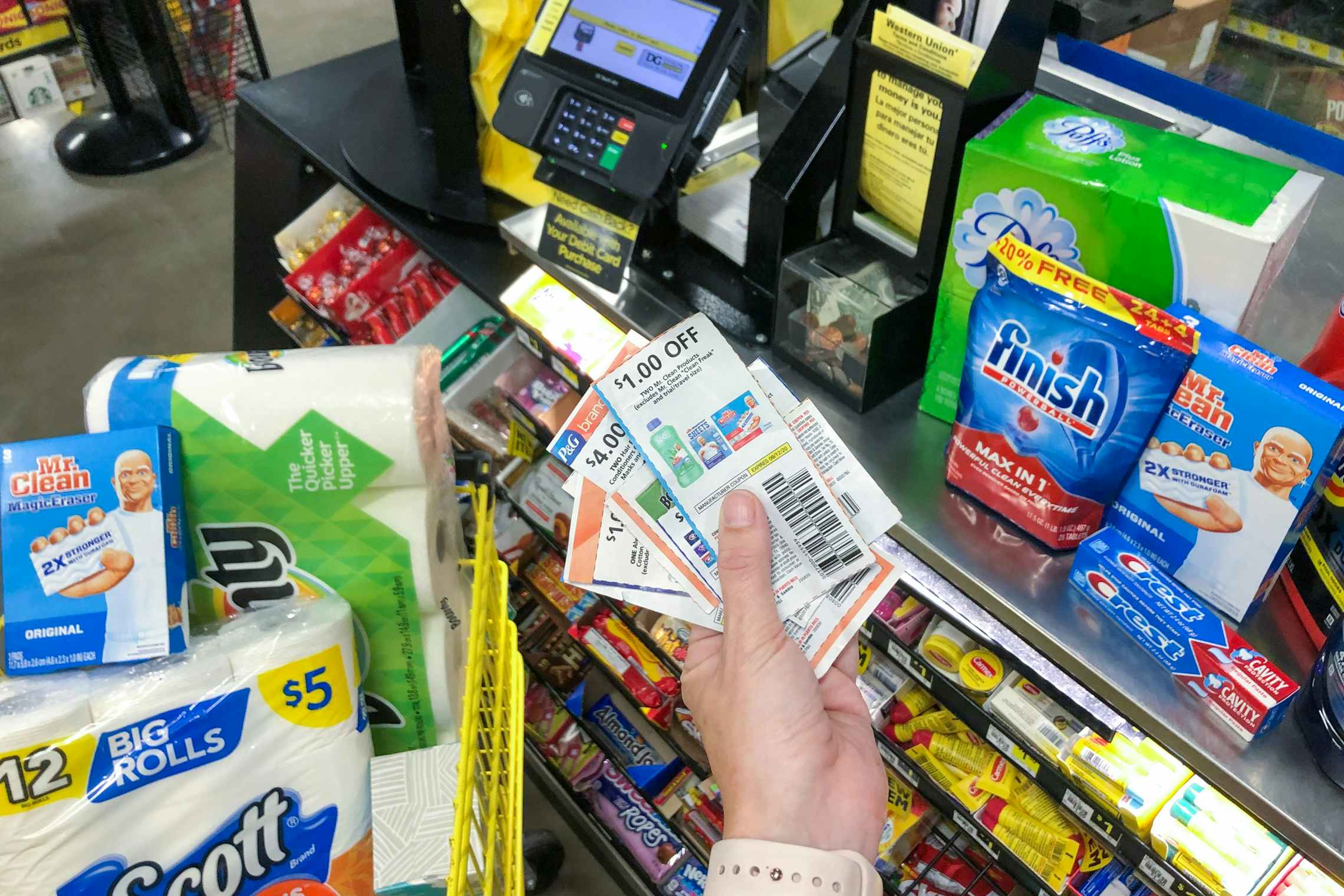 A person holding a stack of coupons next to products inside Dollar General