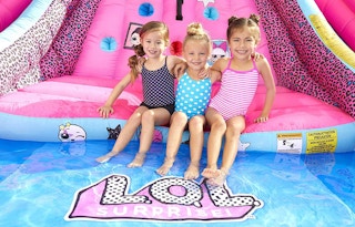Three young girls sitting on a LOL Surprise water slide