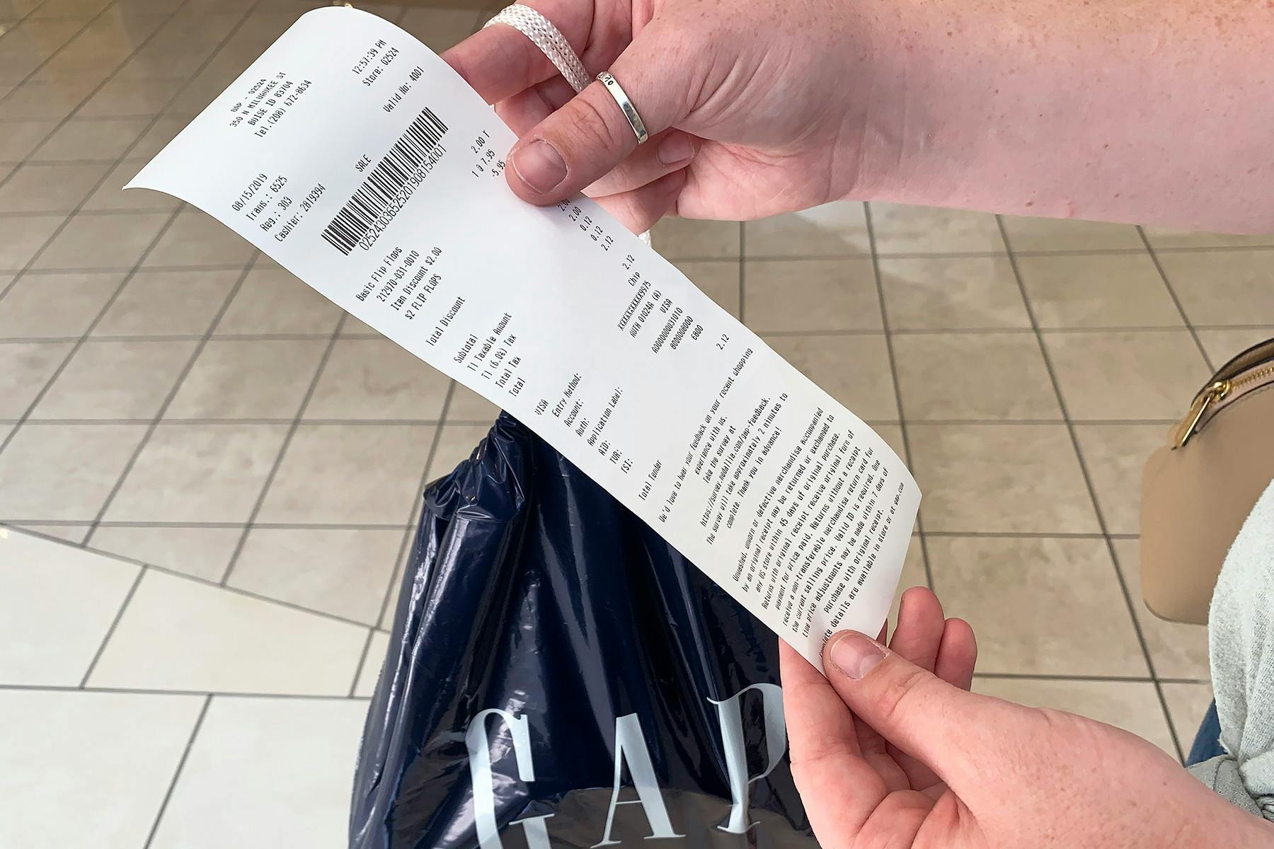 Someone holding up a receipt for a GAP purchase with a GAP bag