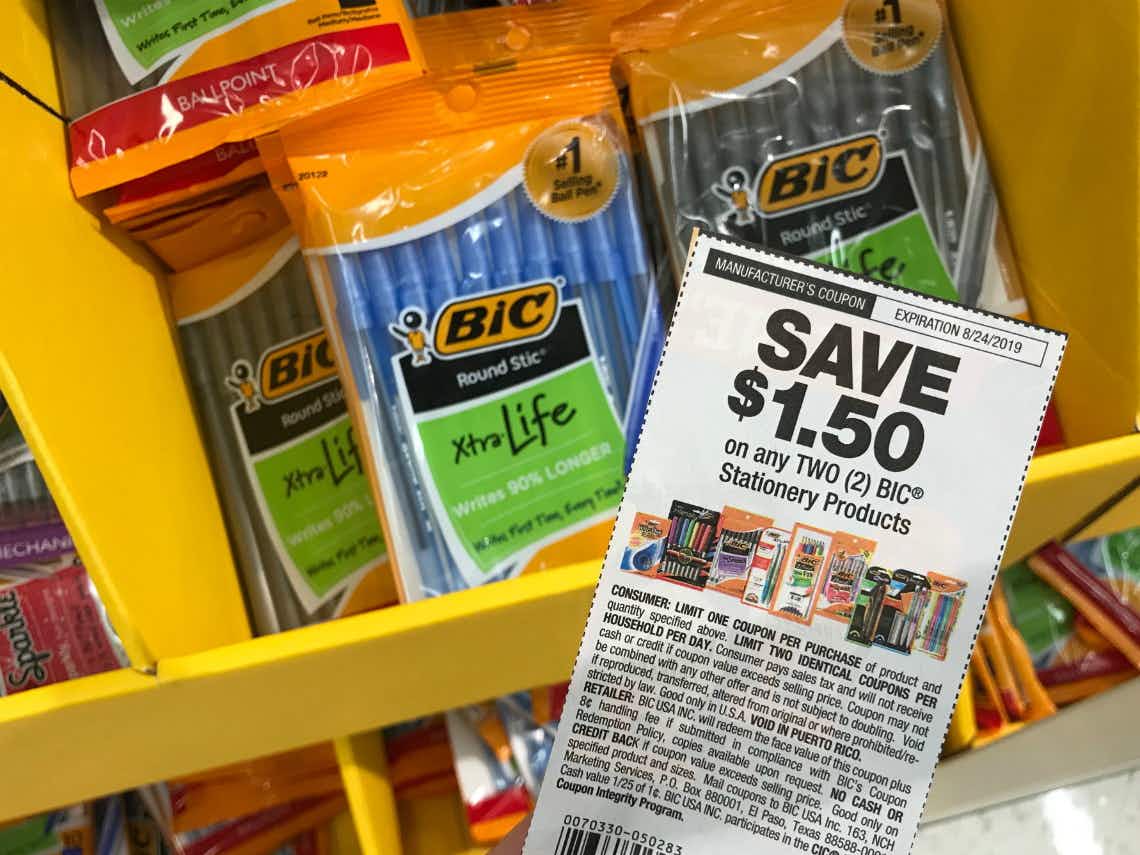 A manufacturer coupon for $1.50 off any 2 BIC Stationary Items being held above a shelf of BIC pens inside Target.