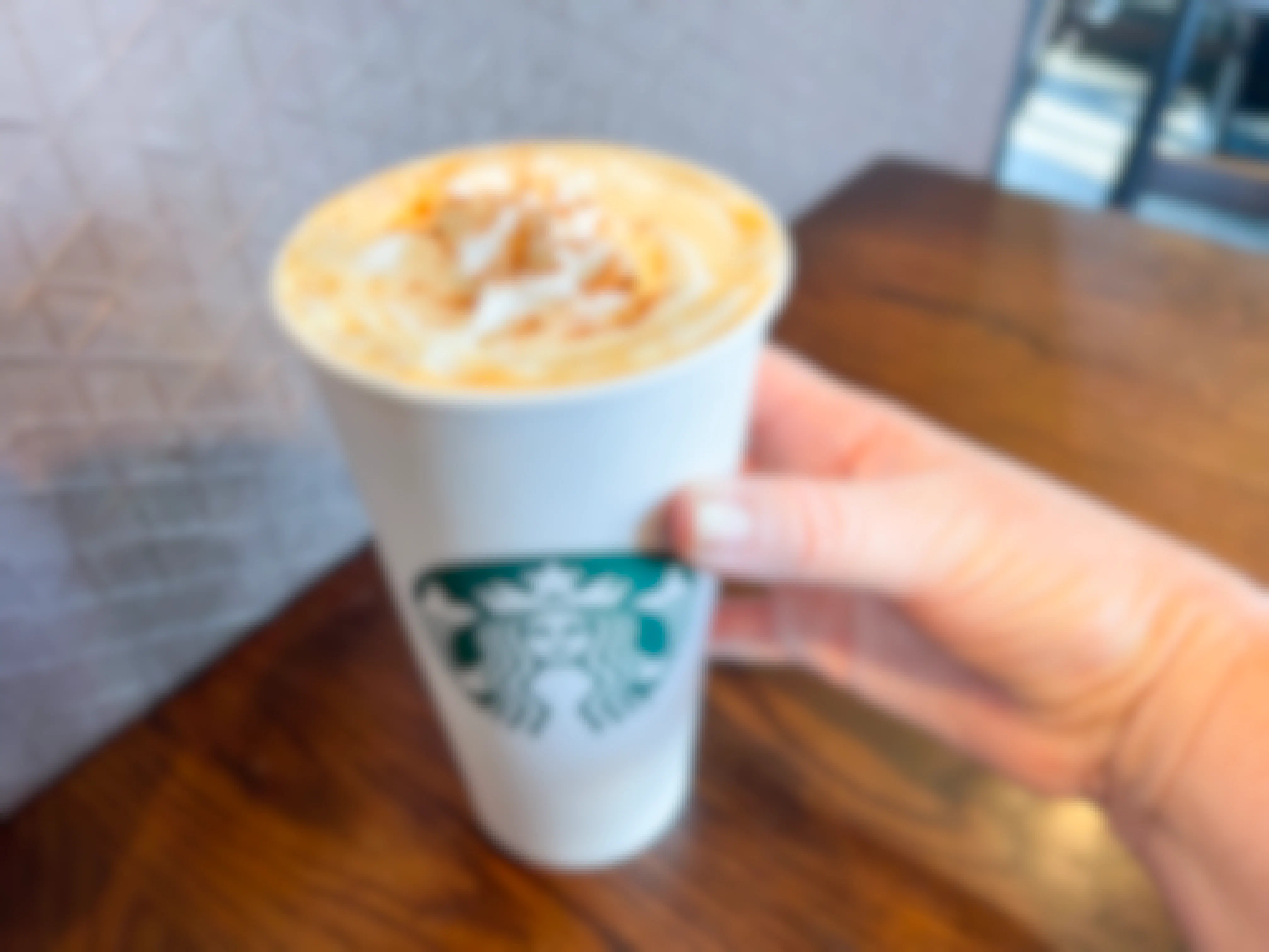 Hand holding A Spiced Latte in a Starbucks cup.