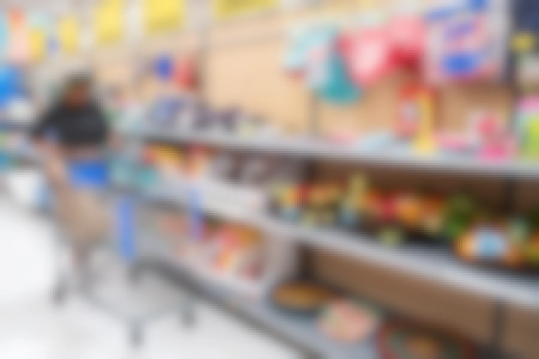 A womand pushing a shopping cart down a clearance aisle in a Walmart store.