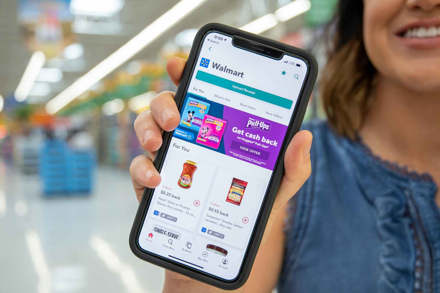 A person holding a smartphone with the ibotta app walmart section displayed.