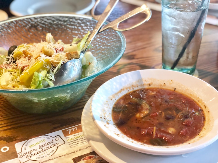 a bowl of soup near to a bowl of salad on a table with a menu on table 