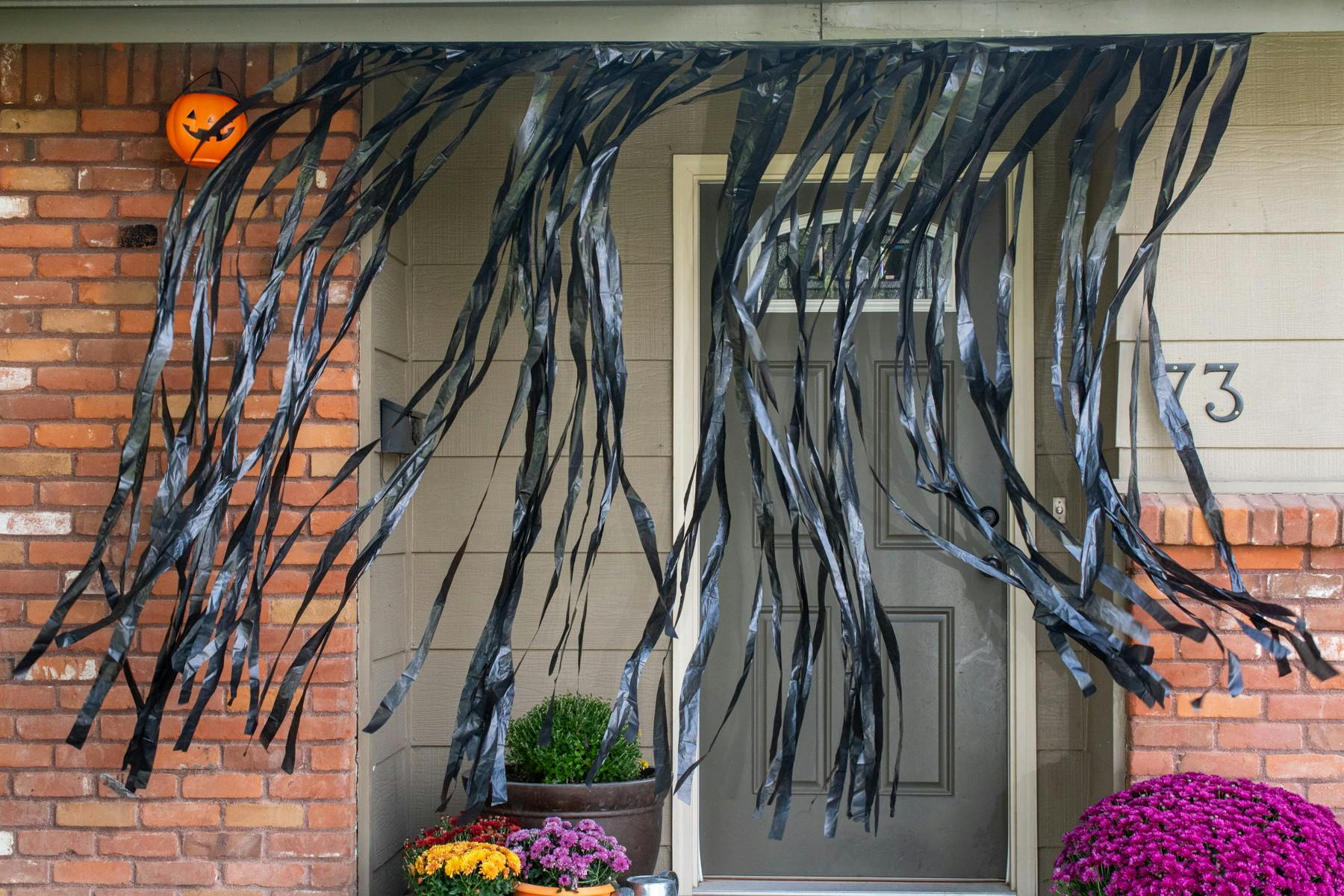 Black trash bags cut into strips hanging on the ceiling of a front porch for decoration.