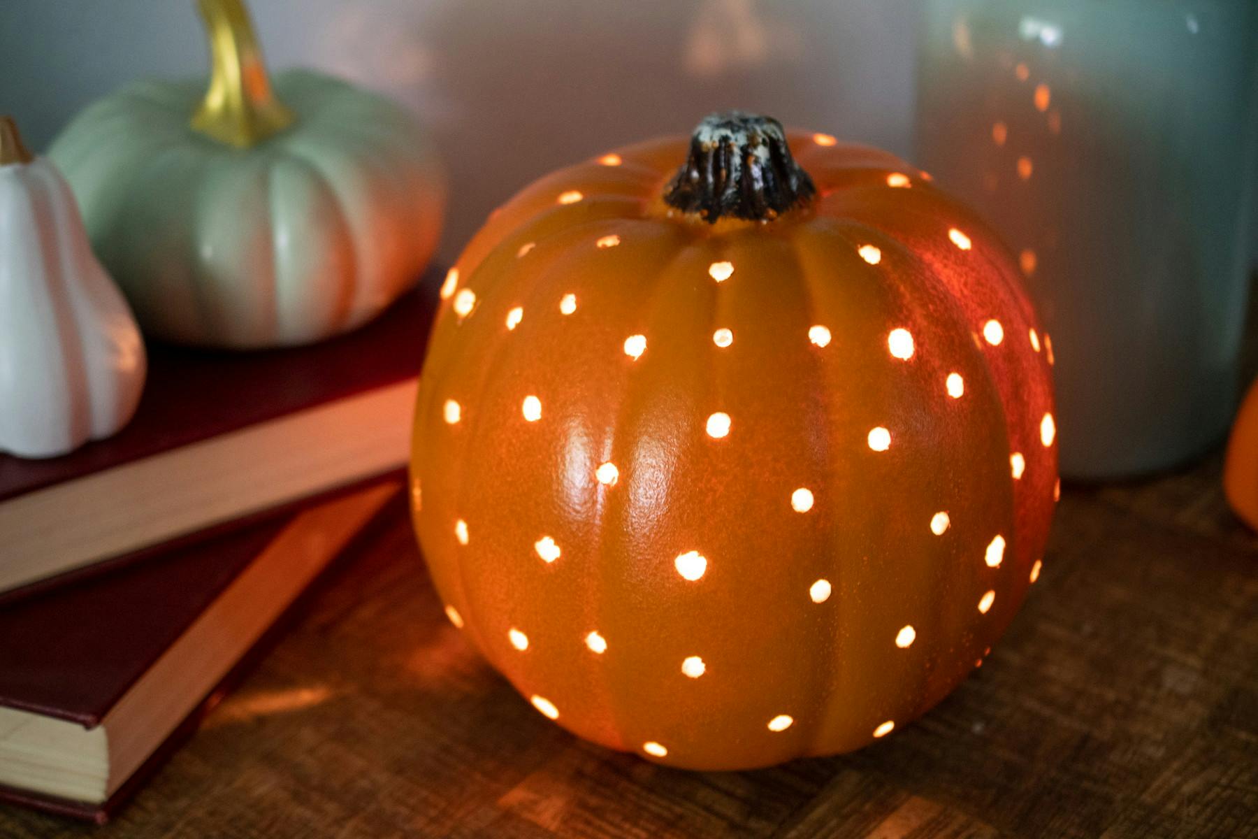 A plastic pumpkin with small drill holes all over it, and light shining through.