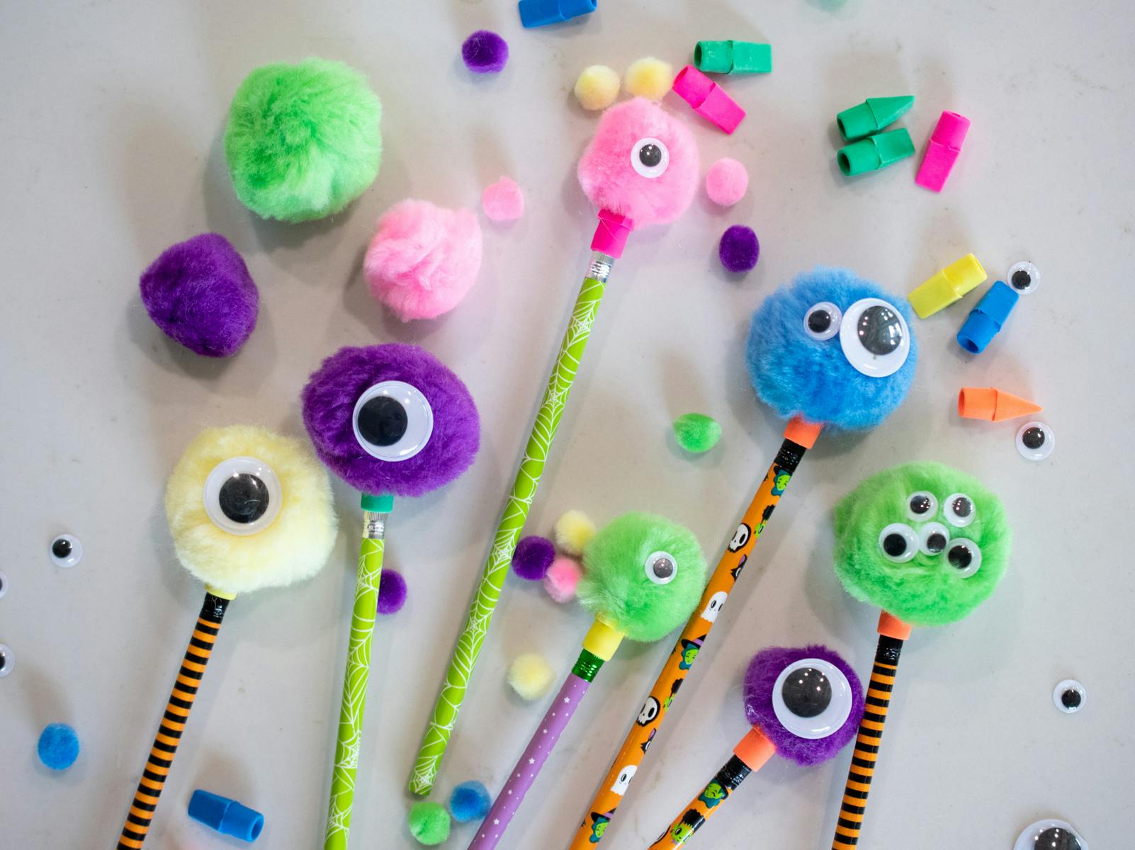 Little monsters made of pom pom balls and goggly eyes glued onto Halloween pencils.