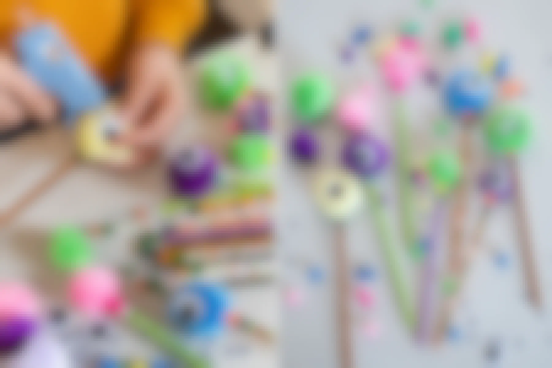 A person making little monsters by hot gluing pom pom balls and goggly eyes onto Halloween pencils.