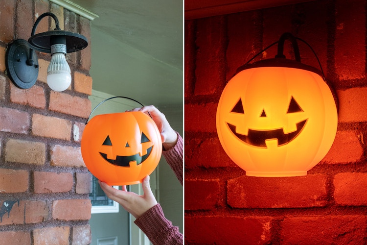 A person covering an outdoor light with a trick-or-treat pumpkin pail, and the pumpkin pail glowing at night.