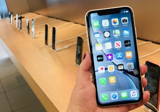hand holds iphone in front of an iphone display in the apple store