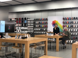 An apple store employee helping a customer inside the Apple Store.