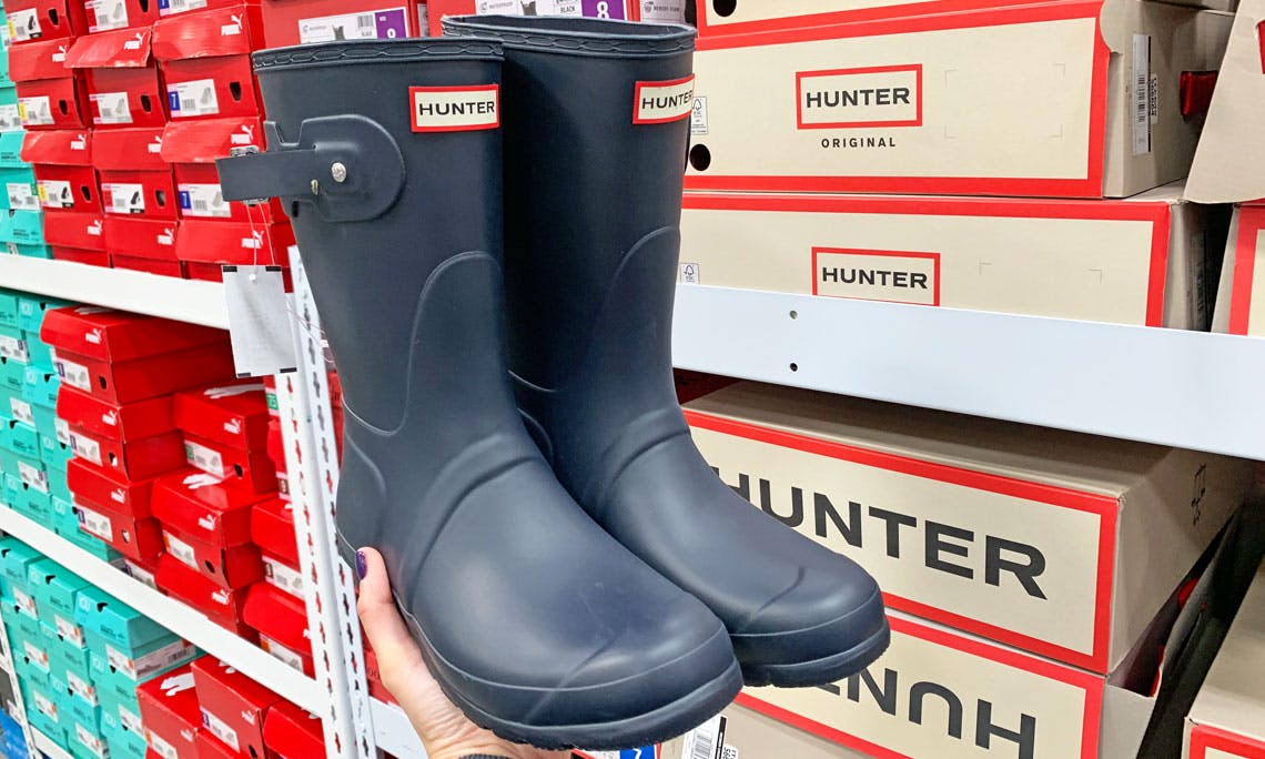 A person holding up a pair of Hunter Boots.