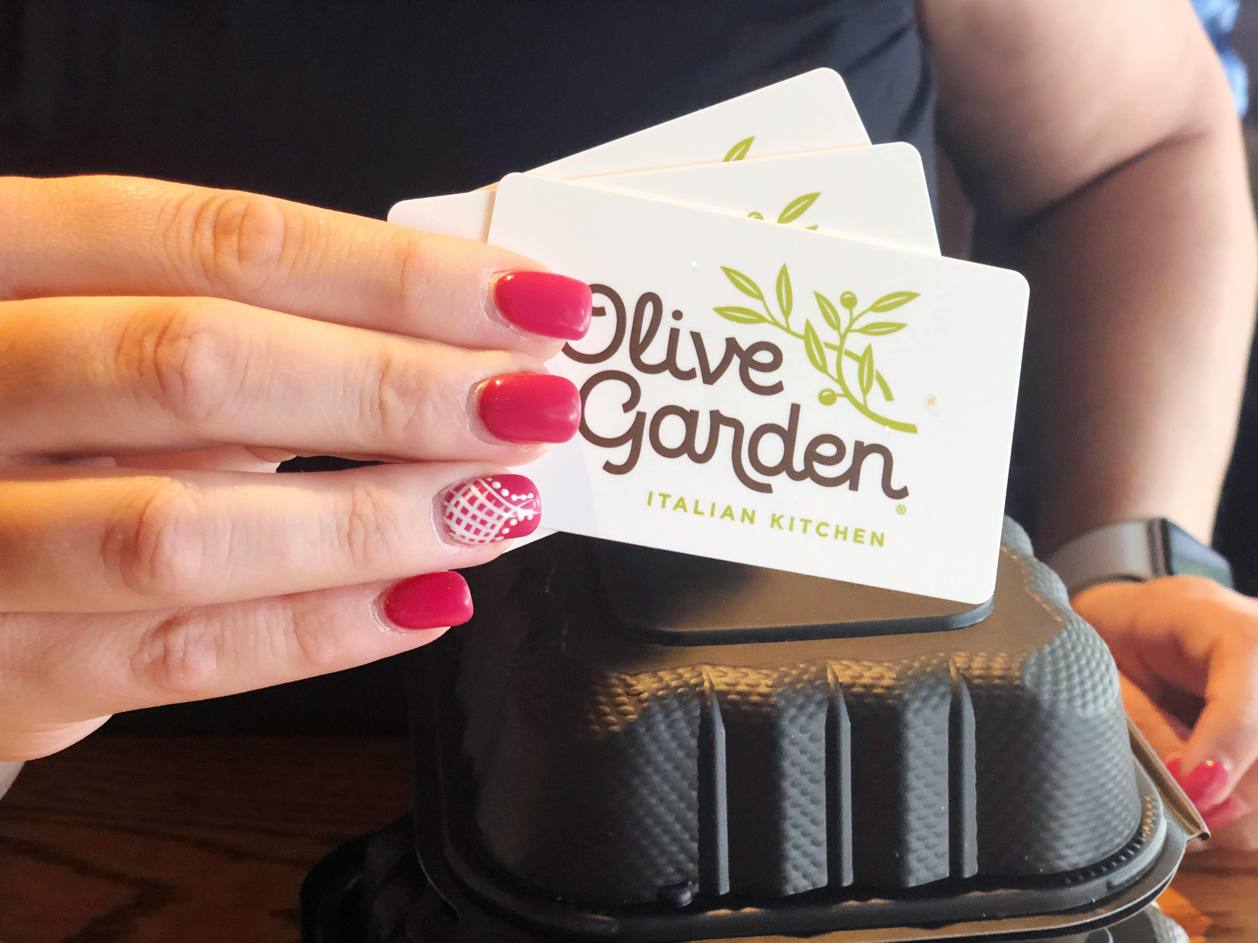 A person holding olive garden gift cards.