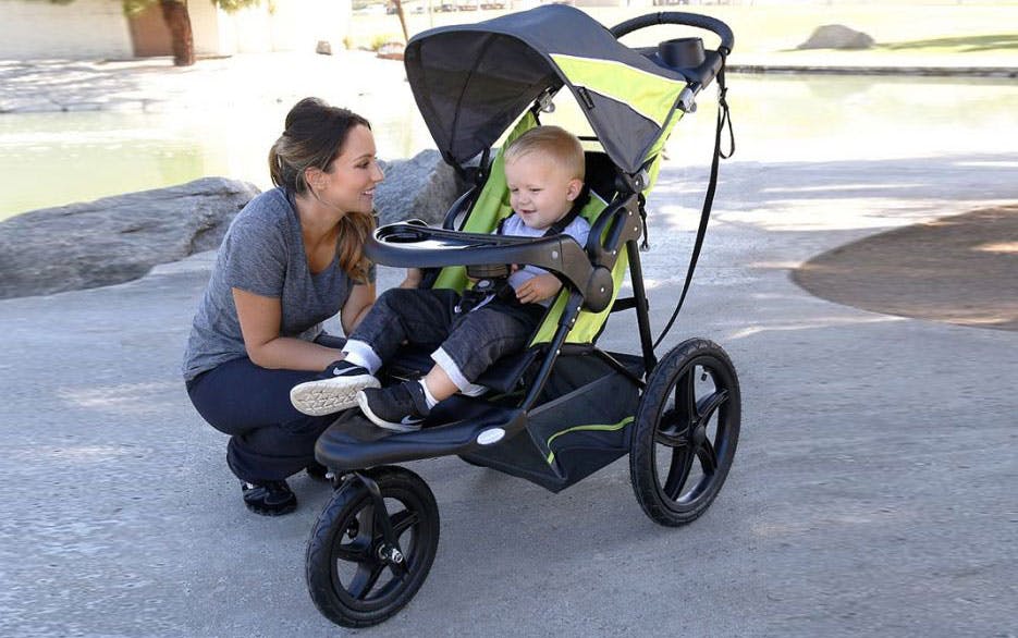 a woman crouching next to a toddler in a stroller