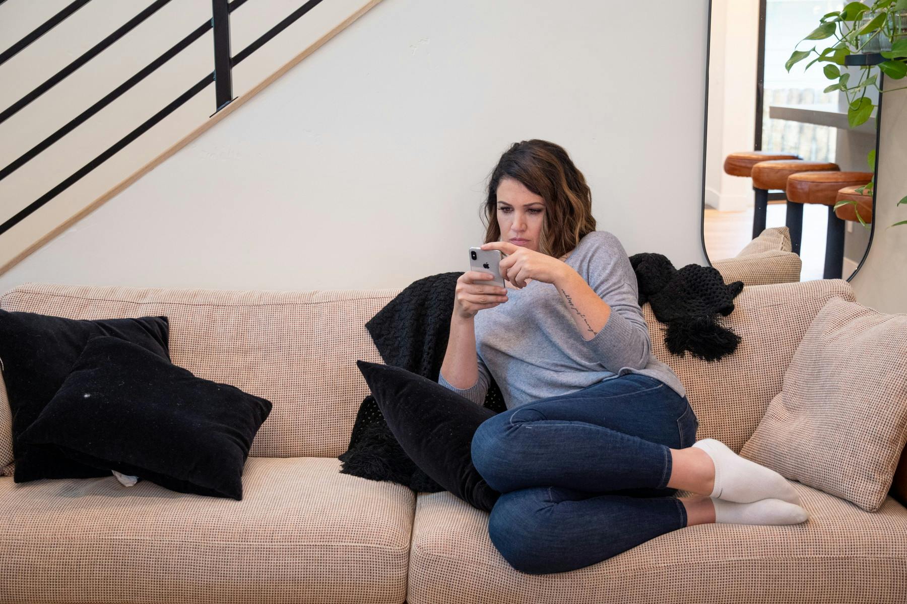 A woman looking at a cell phone while sitting on a sofa.