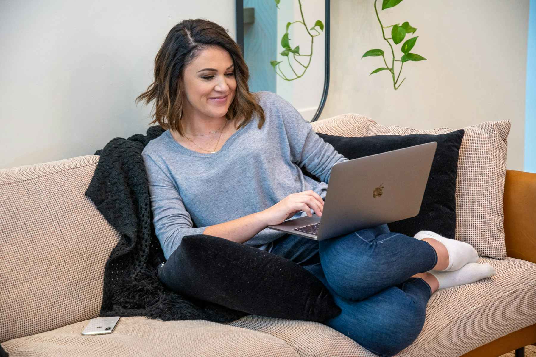 A woman sitting on a sofa looking at a laptop computer