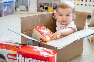 cute baby sits inside a box with huggies around her