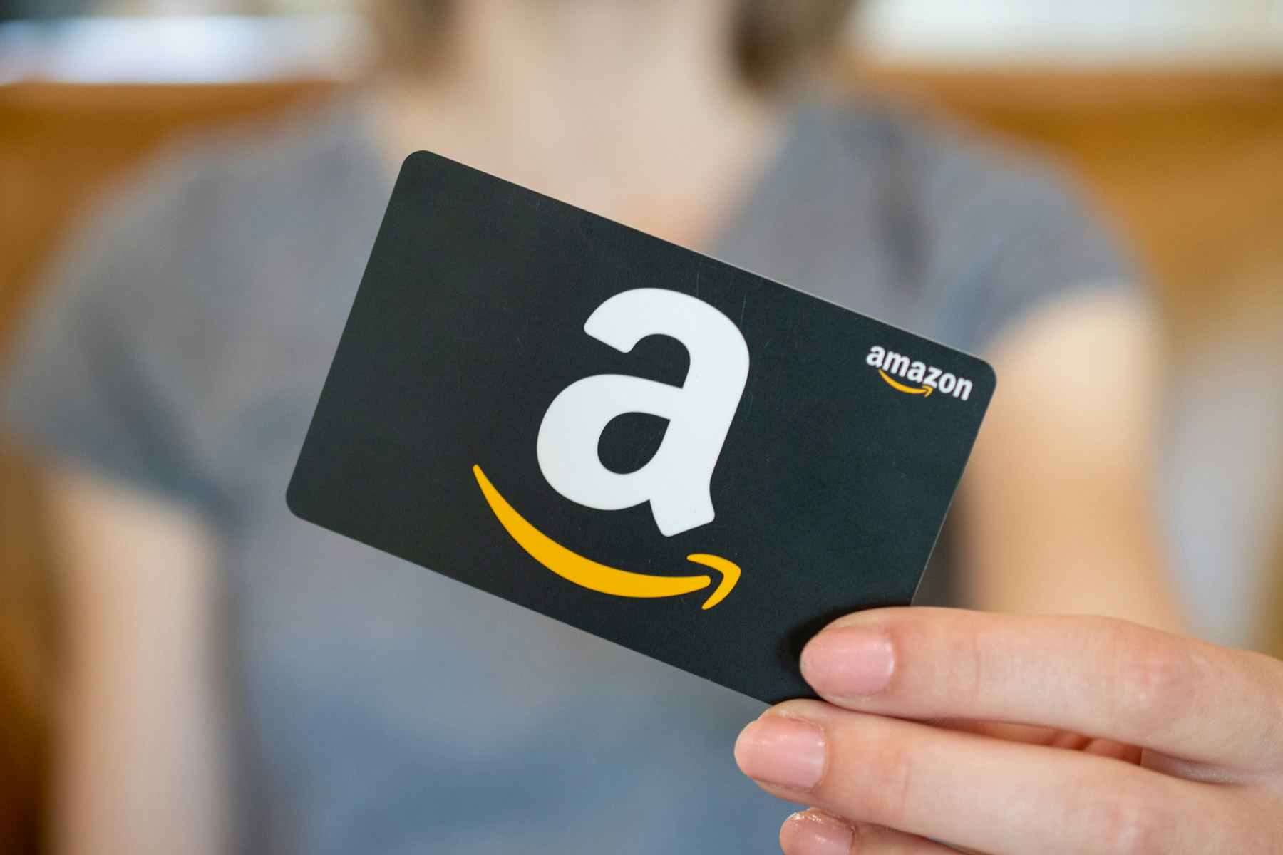 A woman holding an amazon gift card in front of her
