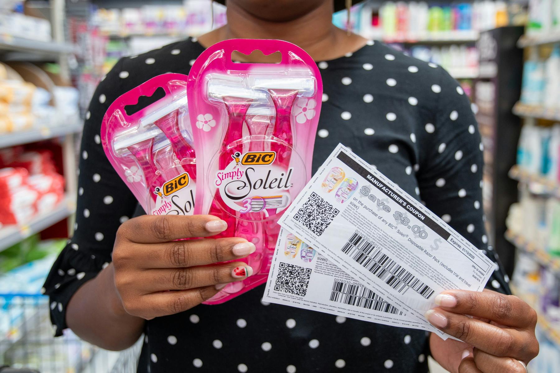 A woman holding two coupons and two bic soleil razor packs.
