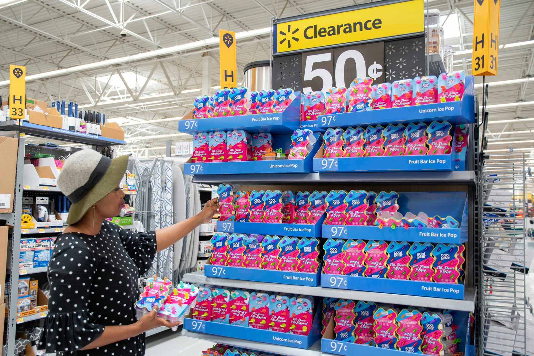 woman at a Walmart endcap picking up Cool Gear ice pop makers off the shelf that says Clearance 50 cents. 