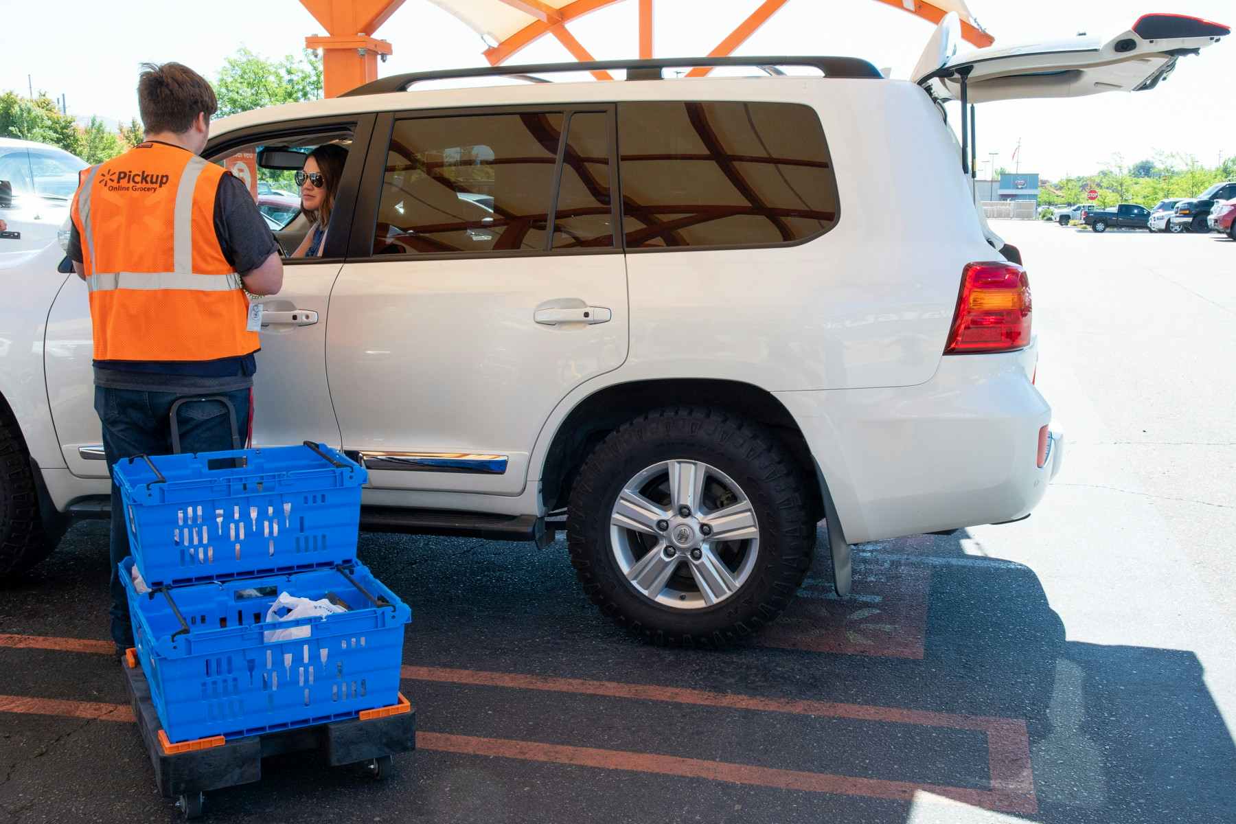 A Walmart employee speaking with a person in a mini van during grocery pickup.