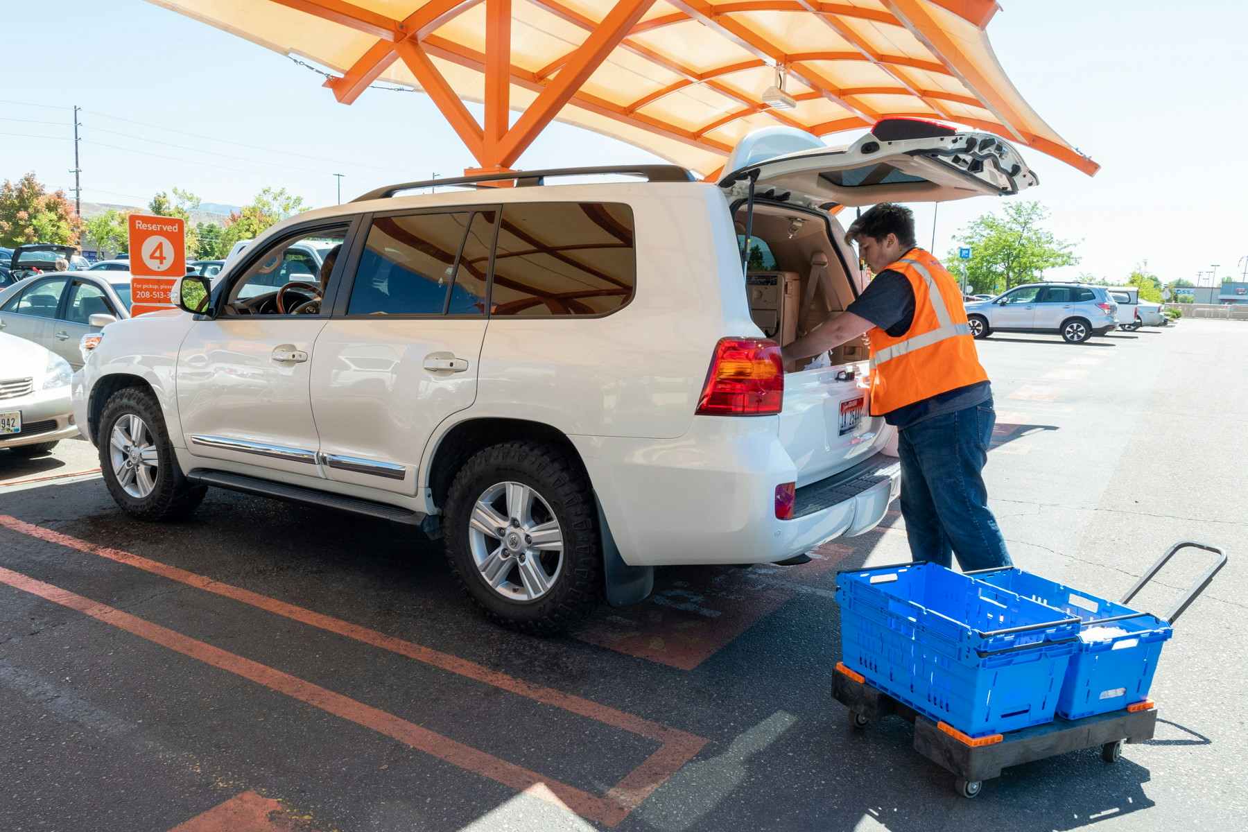 A Walmart employee putting groceries in the back of a white SUV.