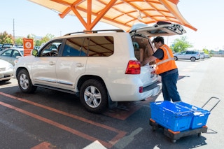 Walmart employee loading up a van with curbside pickup items.
