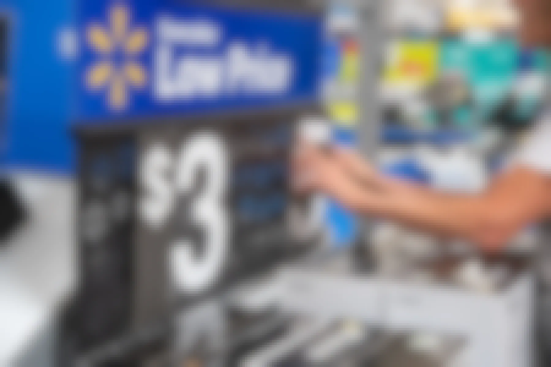 A Walmart employee changing the price on a sign above some printers.
