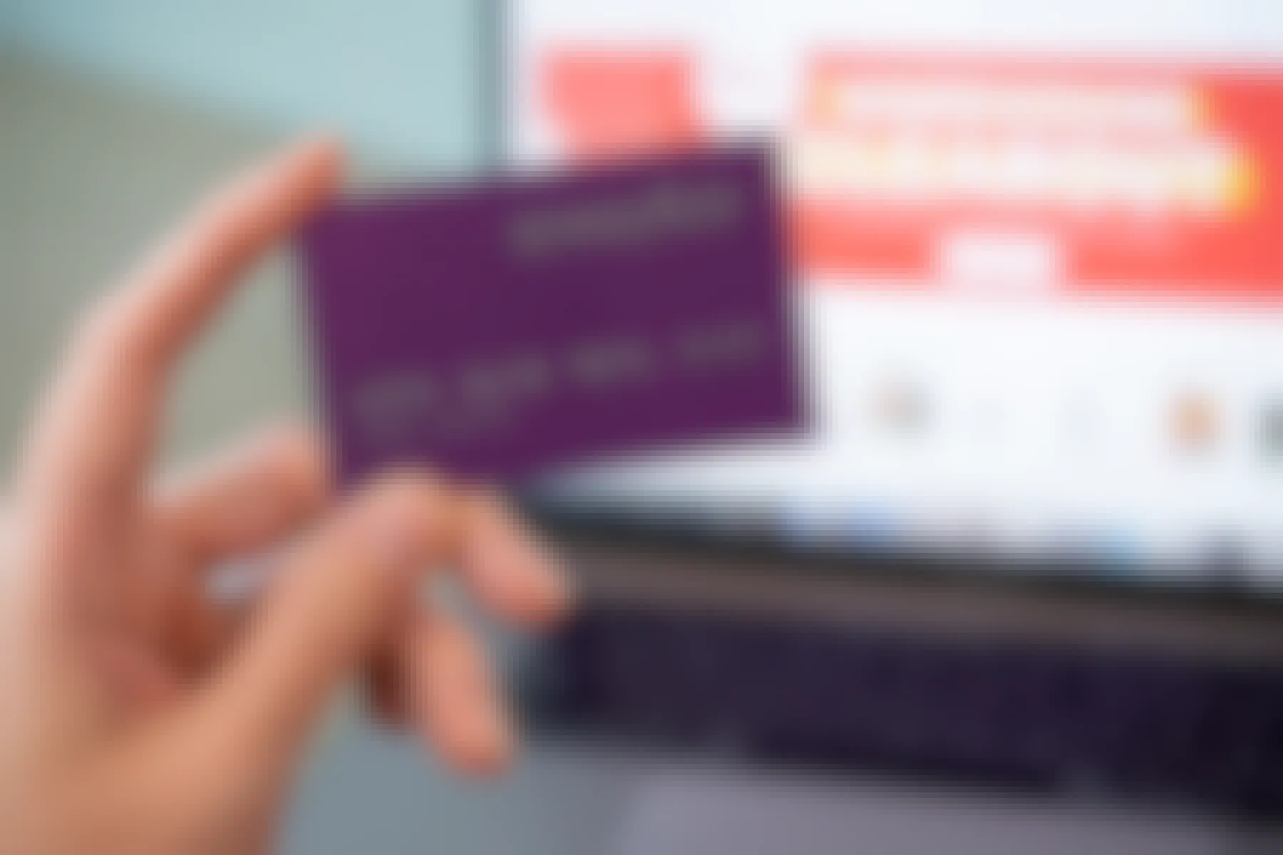 person holding wayfair credit card with homepage and laptop in background
