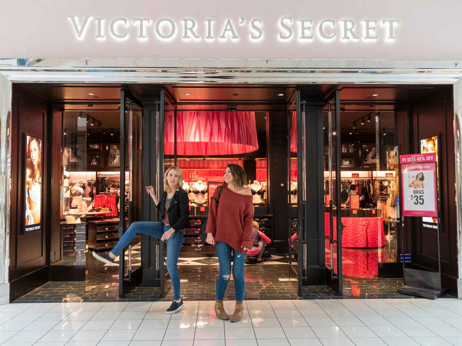 Two women standing at the entrance of a Victoria's Secret store.