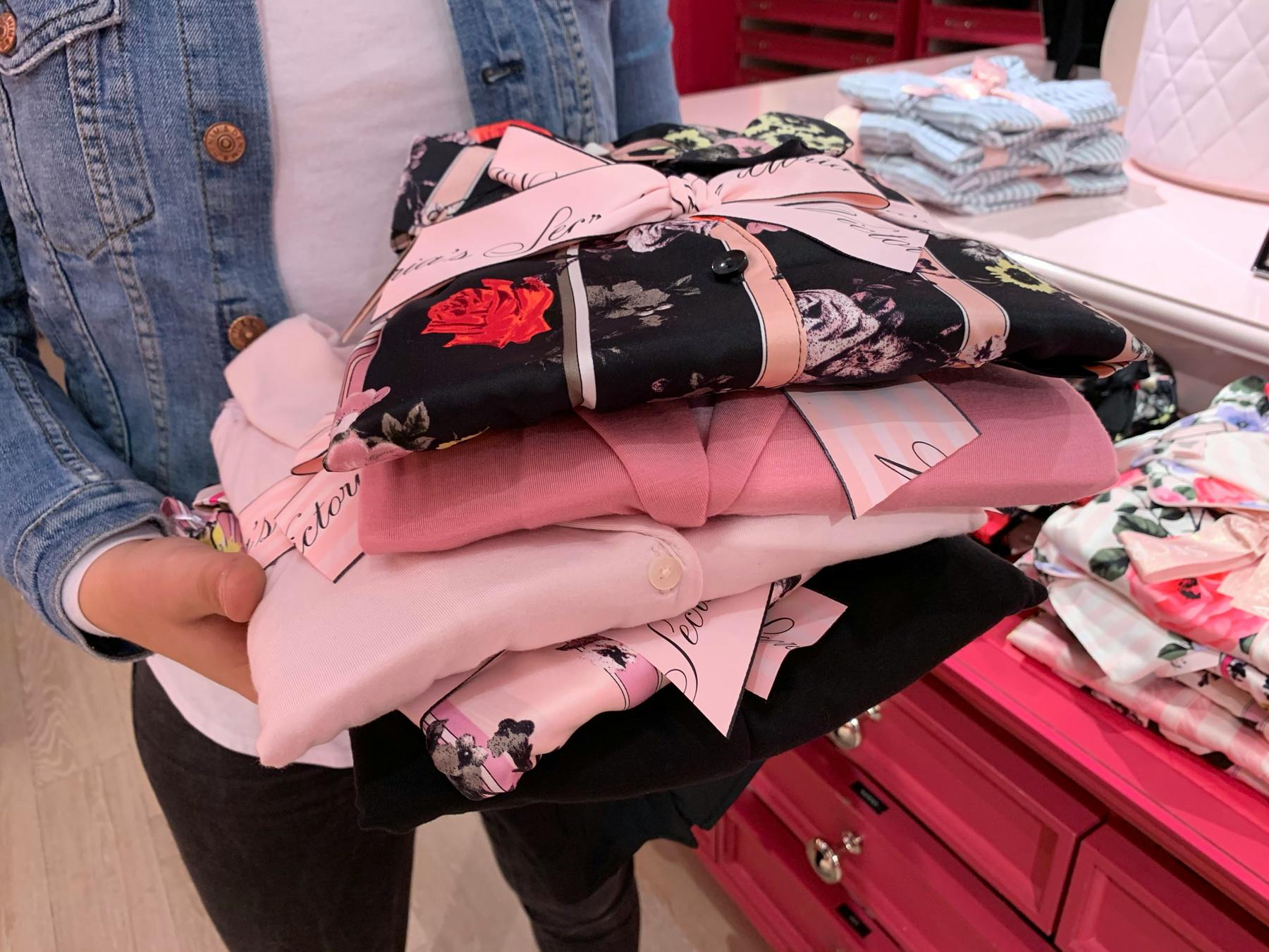 A person holding a stack of pajama sets Victoria's Secret