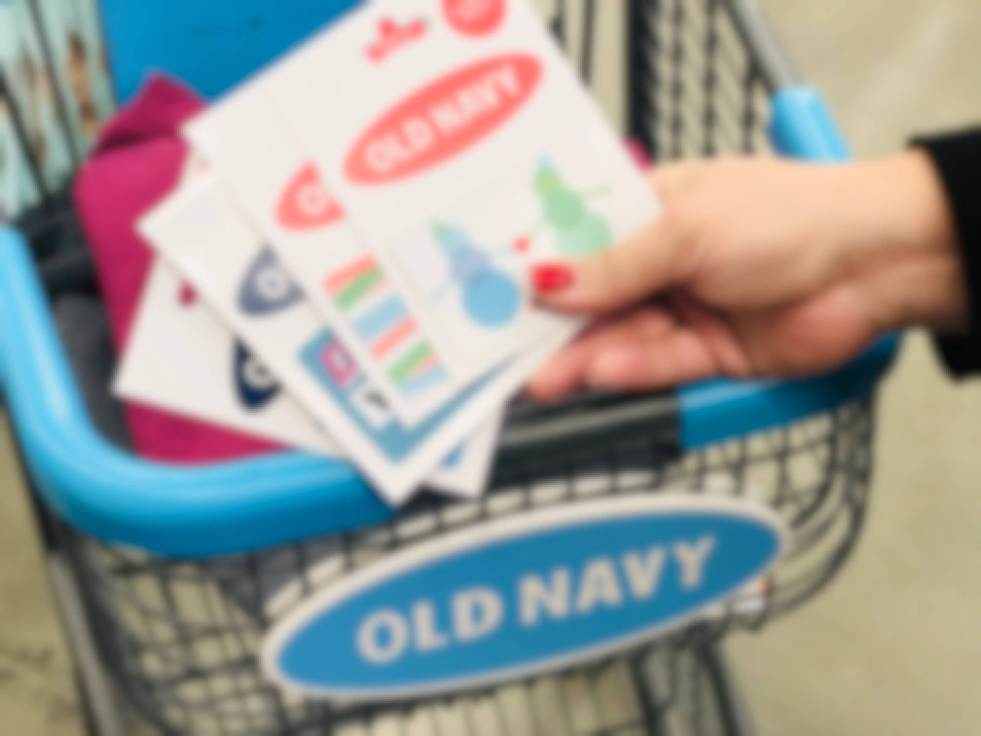 Woman holding four Old Navy gift cards near a cart