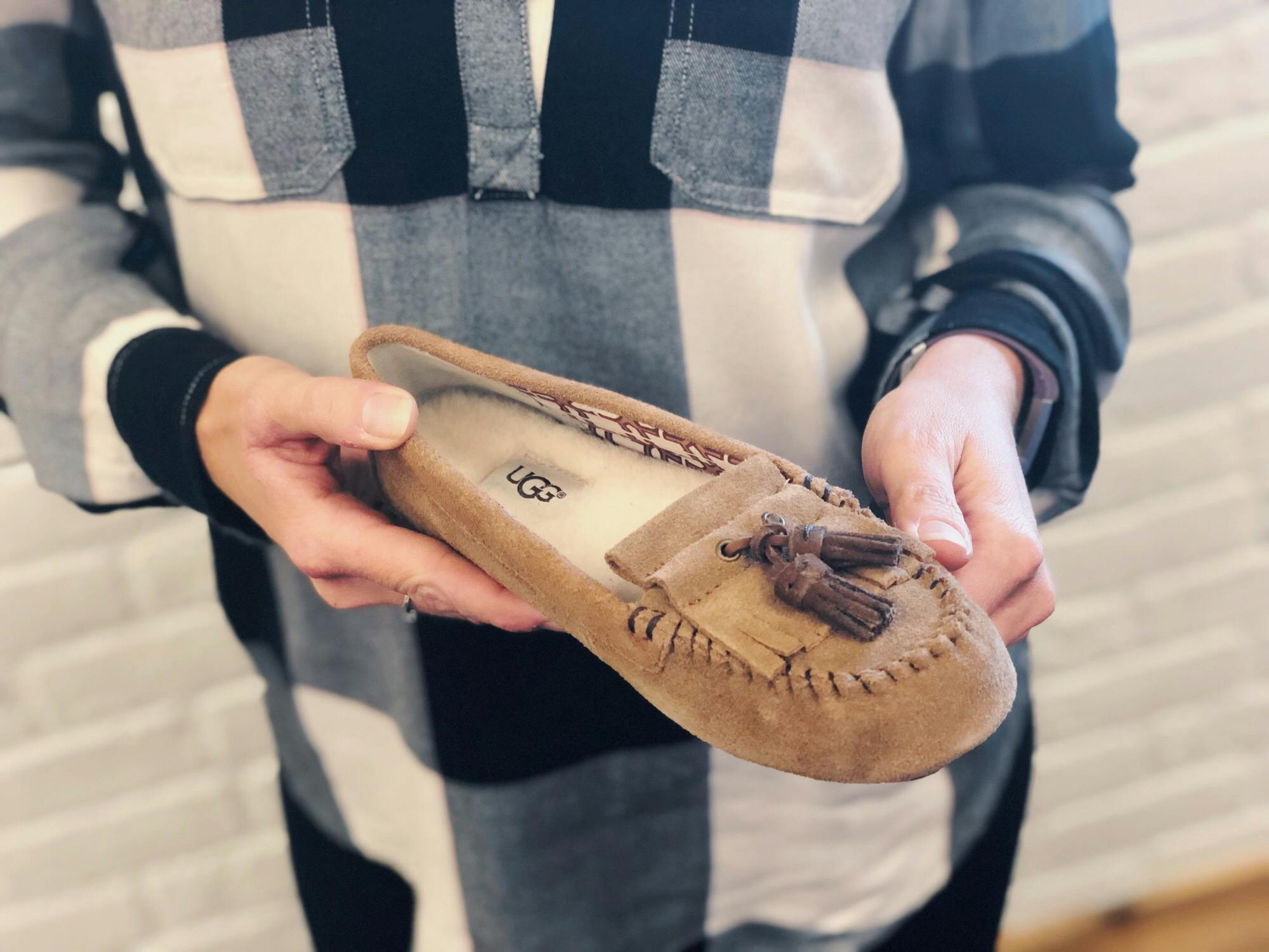 person holding one Ugg moccasin 