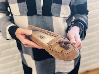 person holding one Ugg moccasin