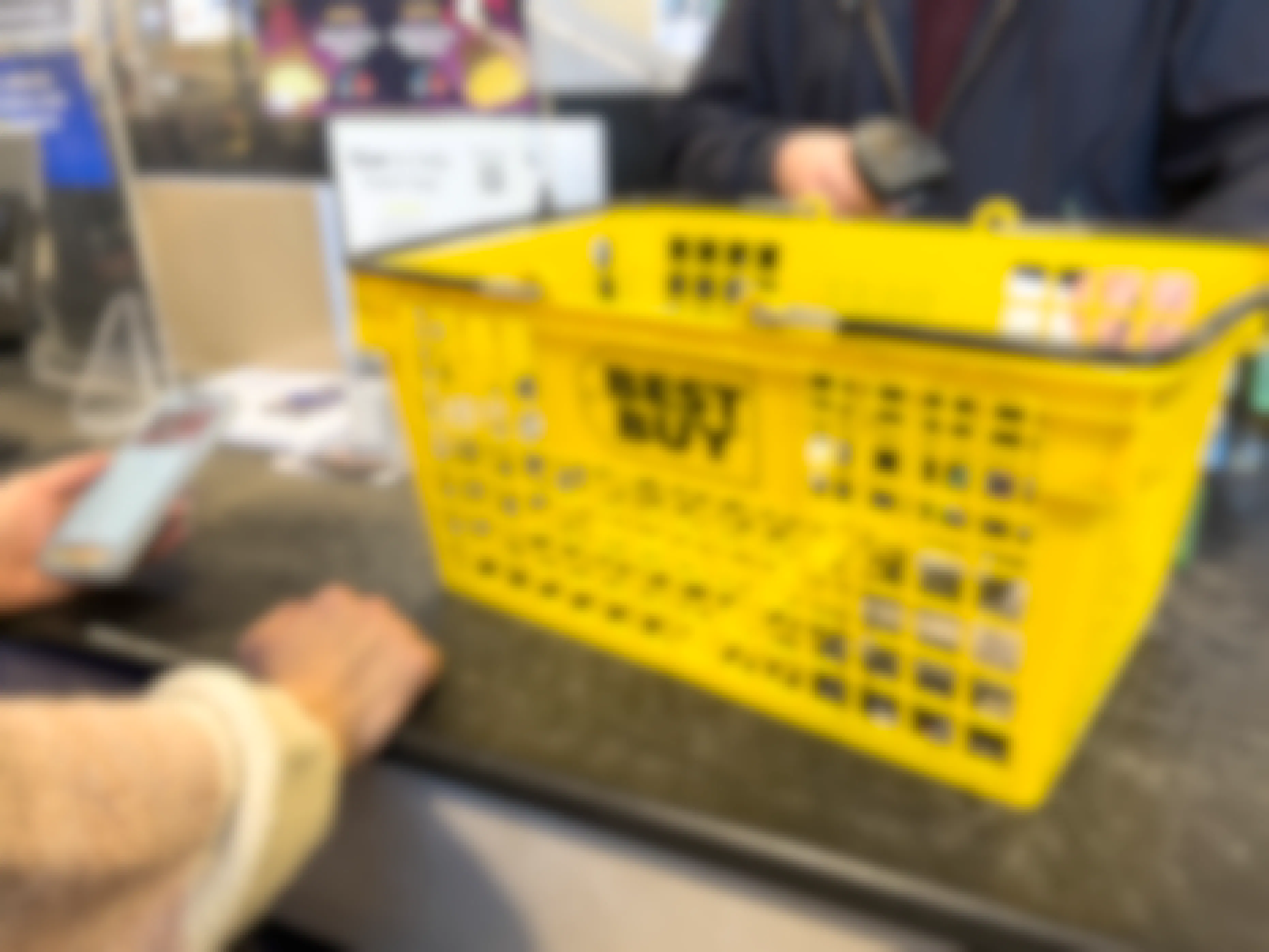 A yellow Best Buy hand basket at a register